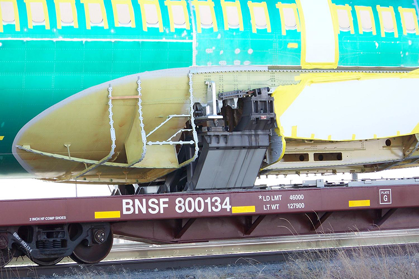 737 Fuselage Attached to BNSF 800134 Flatcar with Anti-Corrosive Primer, Plastic Film, and Tape Applied
